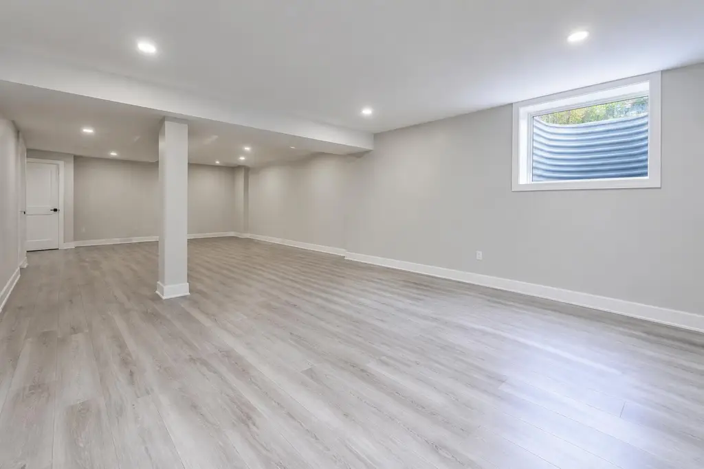 A finished Ontario basement with vinyl plank flooring and an egress window
